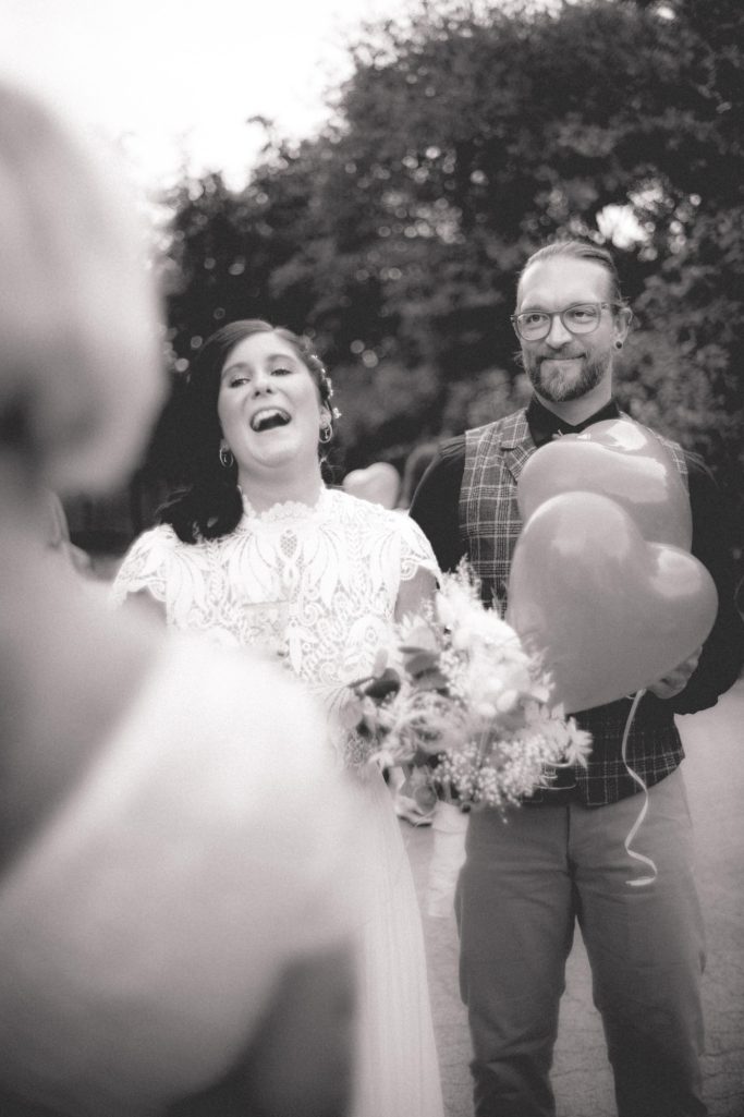 Braut mit Bouquet und herzförmigen Luftballons, lächelnd, in einer festlichen Umgebung.